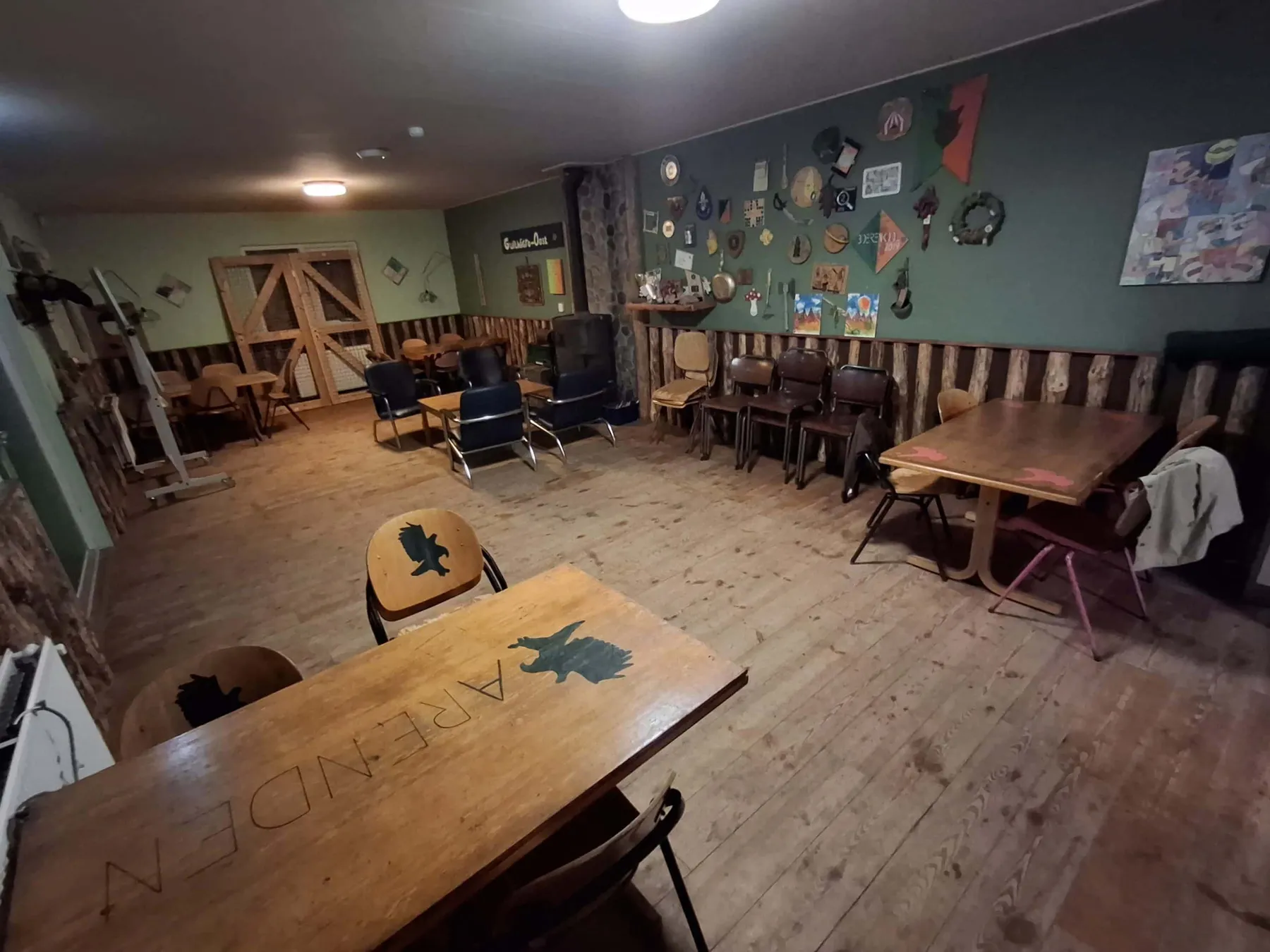 Groen verblijf met houten tafels, stoelen en versierde muren