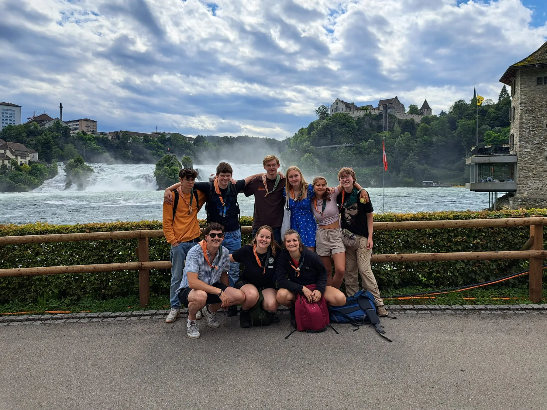 Explorers met rugzakken poseren bij een reling voor een grote waterval
